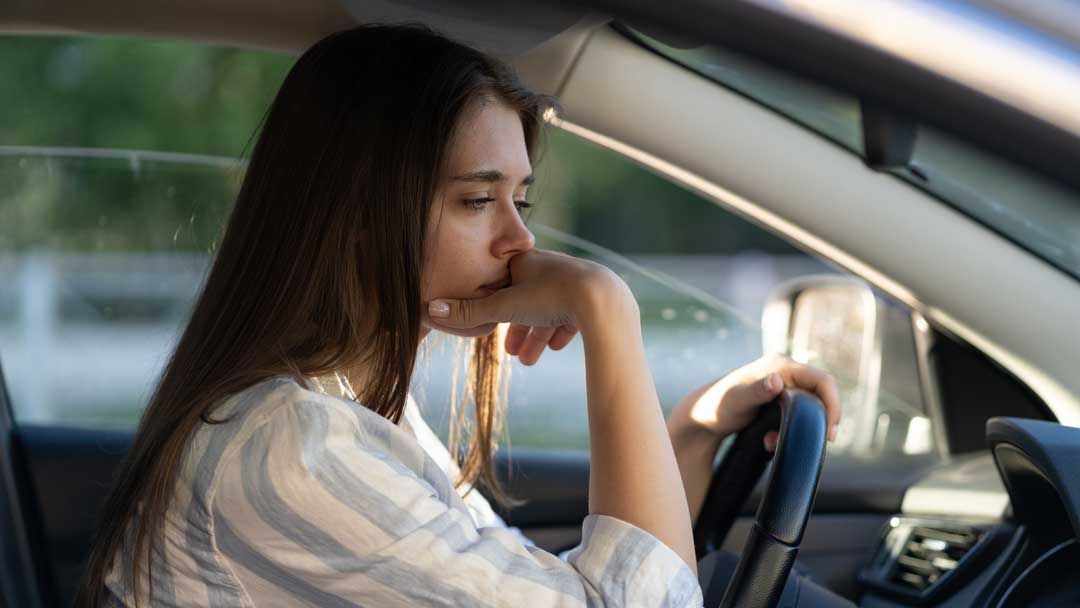 young woman sitting in car with regret